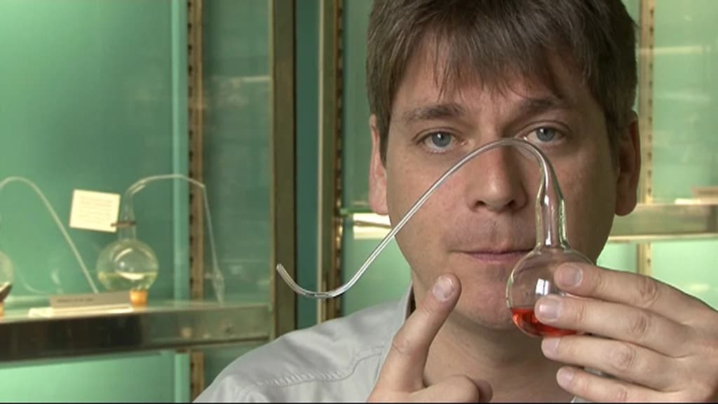 Man holding and pointing at a glass apparatus with red liquid