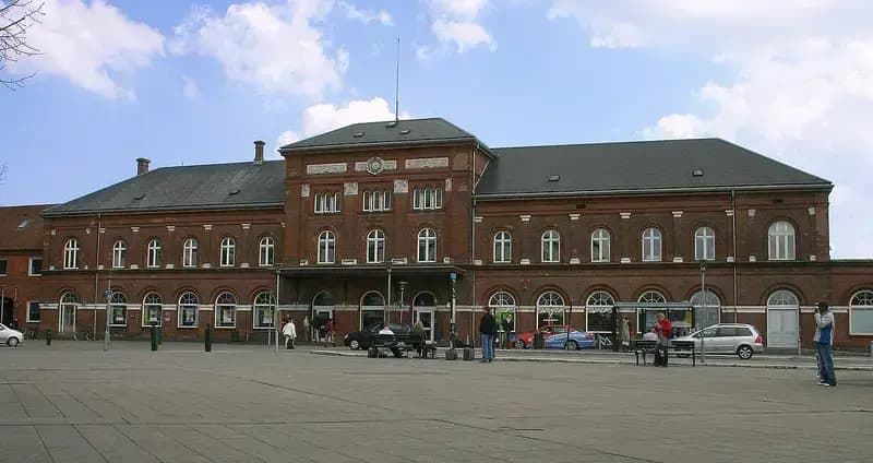 Historic brick train station with people and cars in front